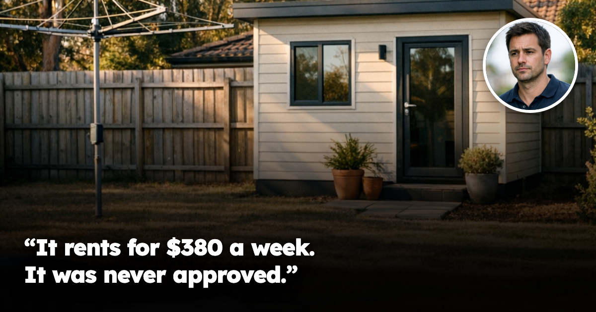 A small self-contained studio or granny flat at the rear of an ordinary Australian suburban backyard in late afternoon light, with a clothesline and paling fence. No people present.