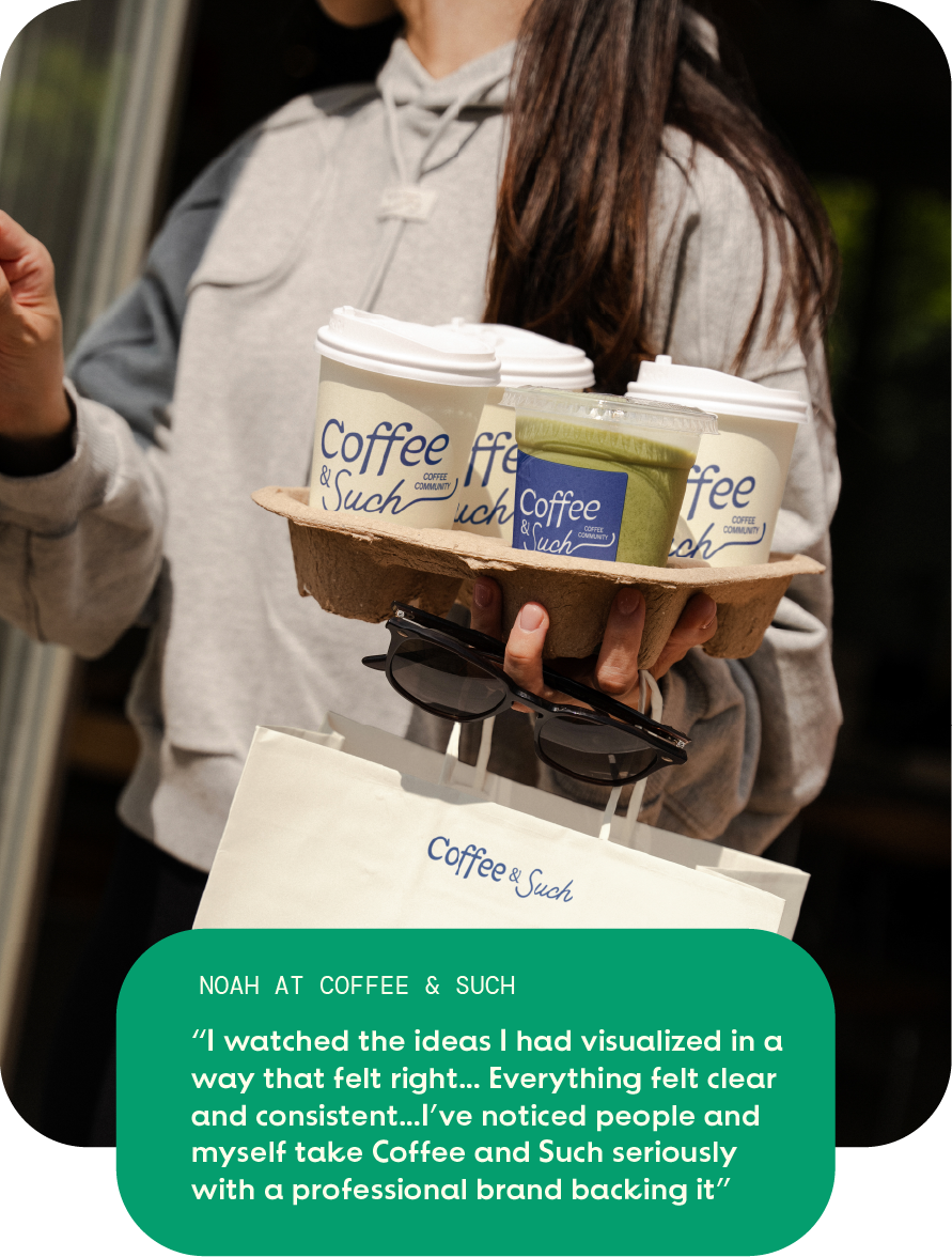 Person holding a tray with three Coffee & Such cups, one green drink, and sunglasses over a branded bag.