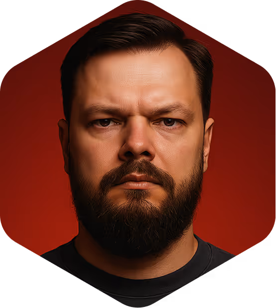 Serious man with short dark hair and full beard against a red background.