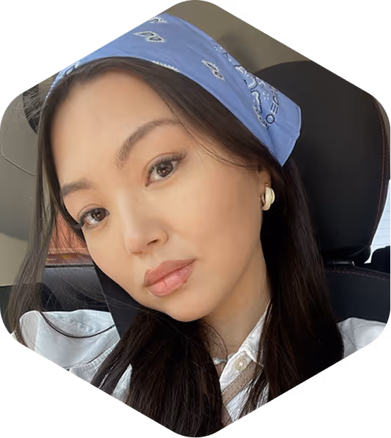 Woman with long dark hair wearing a blue bandana and gold earrings, seated in a car.