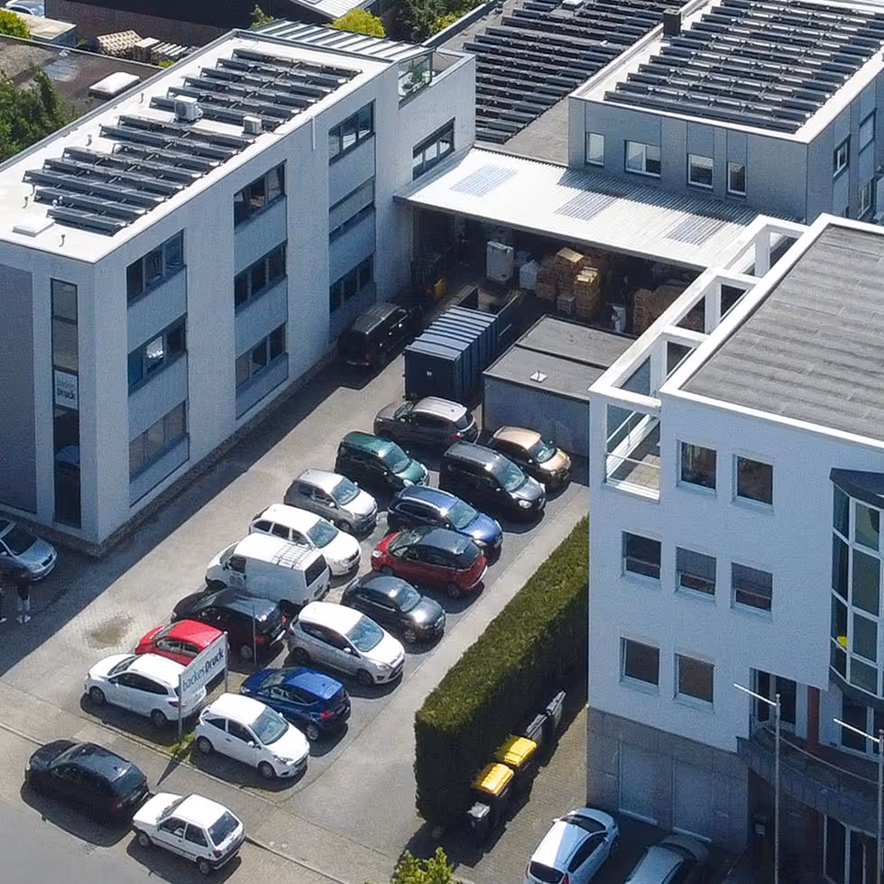 Luftaufnahme des Firmengeländes von backesDruck in Langenfeld mit Produktionshallen und Bürogebäude – moderne Druckerei mit eigener Solaranlage.