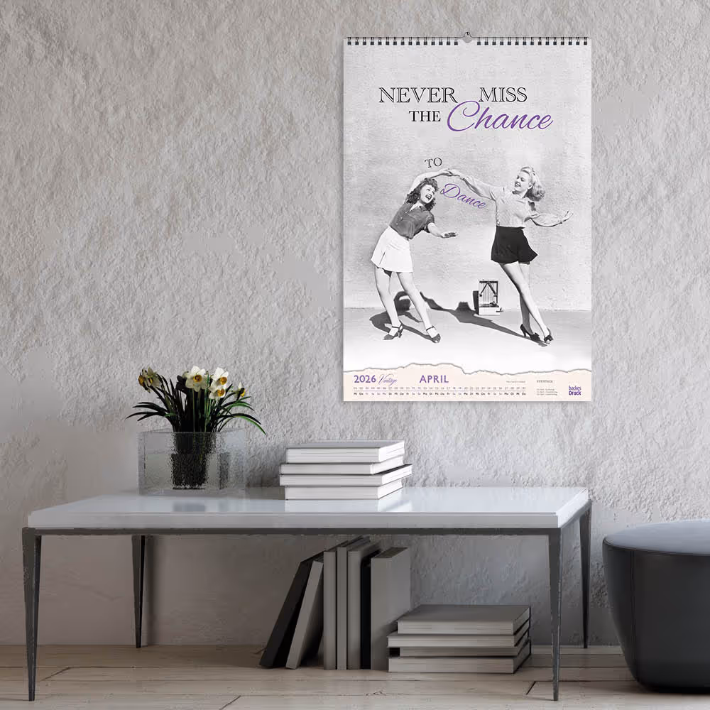 Mockup des Monatsmotivs April aus dem backesDruck Kalender 2026: Vintage-Tanzmotiv mit zwei Tänzerinnen, als Wandkalender in dezentem, klassischem Wohnraum.