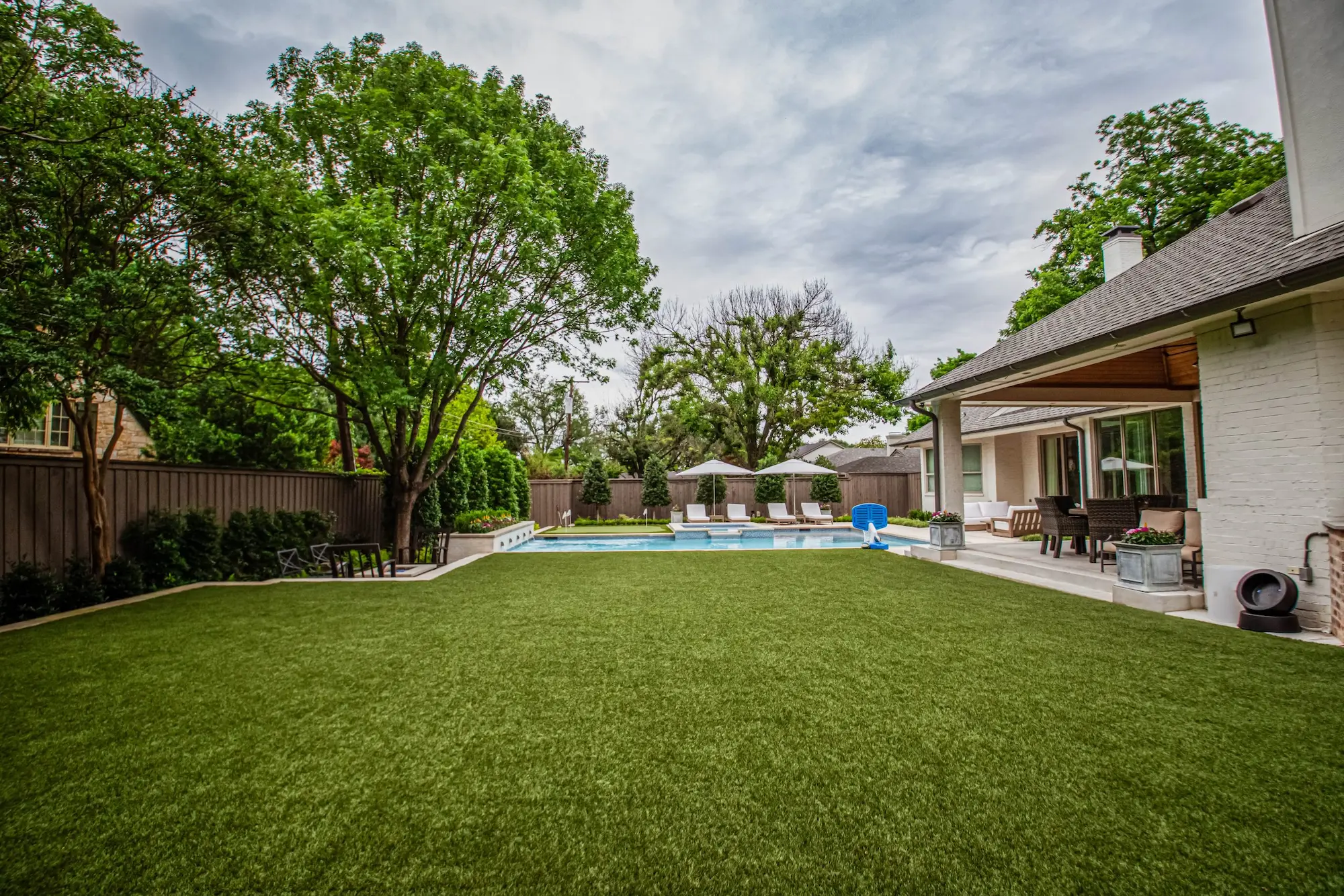 A backyard featuring lush artificial grass surrounding a sparkling pool, creating a serene outdoor oasis