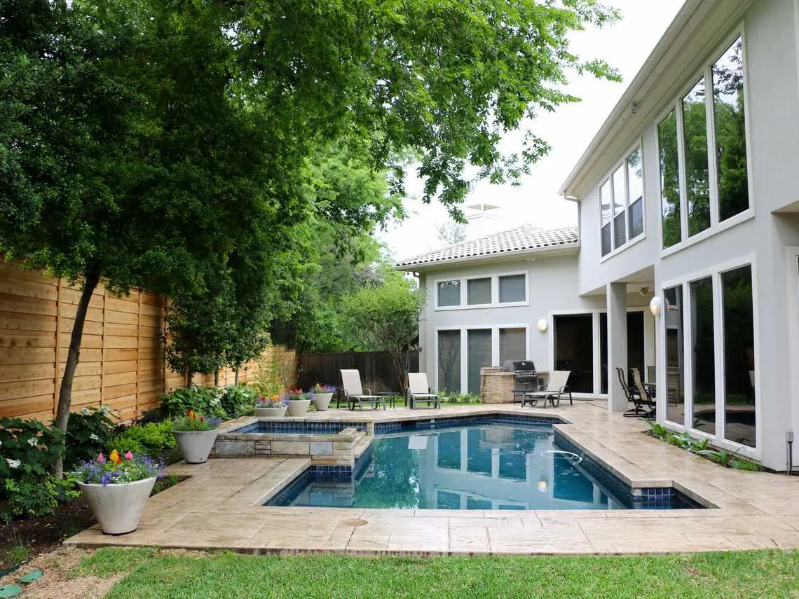 A serene backyard featuring a sparkling pool surrounded by a spacious patio area, perfect for relaxation and gatherings