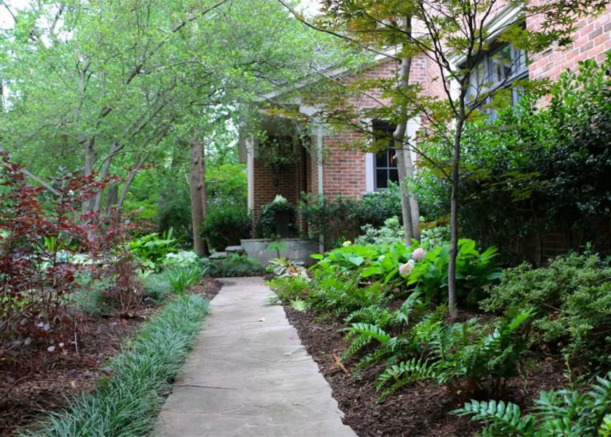 A scenic walkway lined with vibrant plants and shrubs leading up to a charming house.