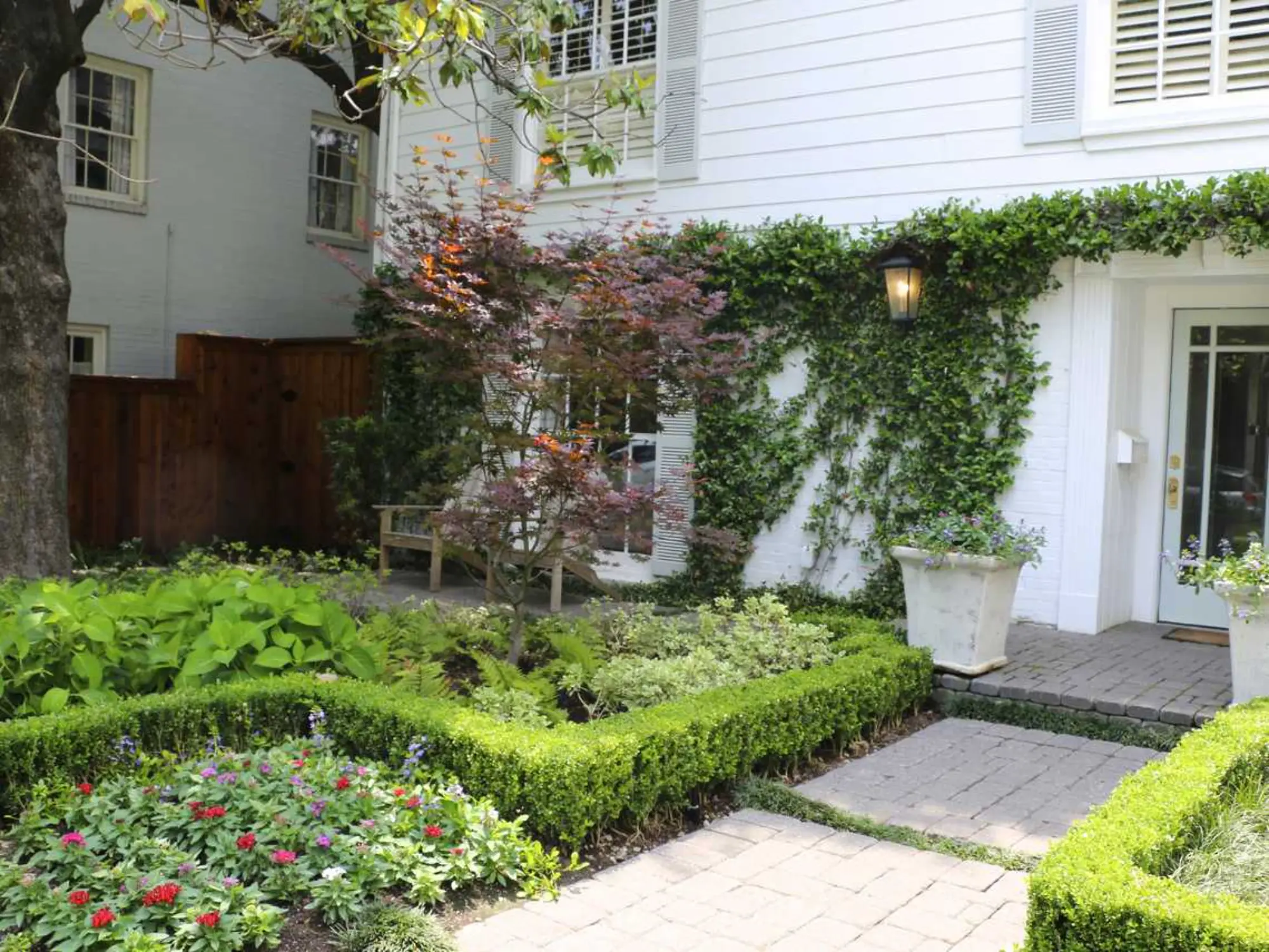 A white house surrounded by a lush garden and neatly trimmed shrubs, showcasing a serene outdoor space.