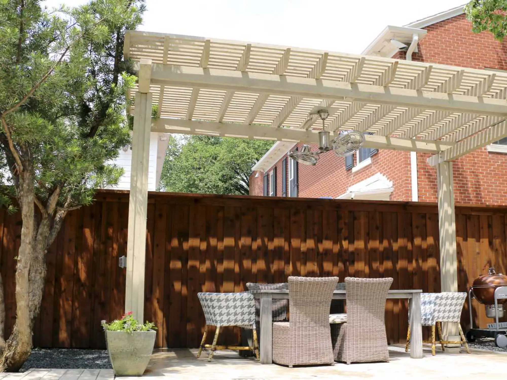 A cozy patio featuring a wooden pergola and comfortable chairs, perfect for relaxation and outdoor gatherings.