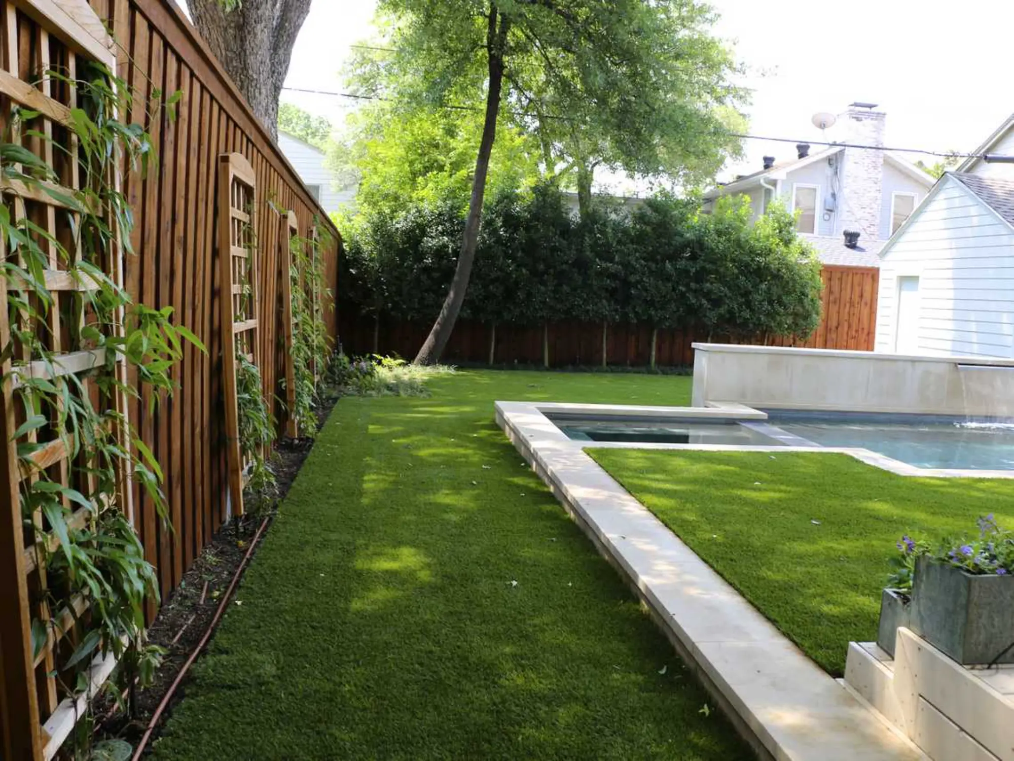 A backyard featuring lush artificial grass surrounded by a sturdy wooden fence, creating a cozy outdoor space.