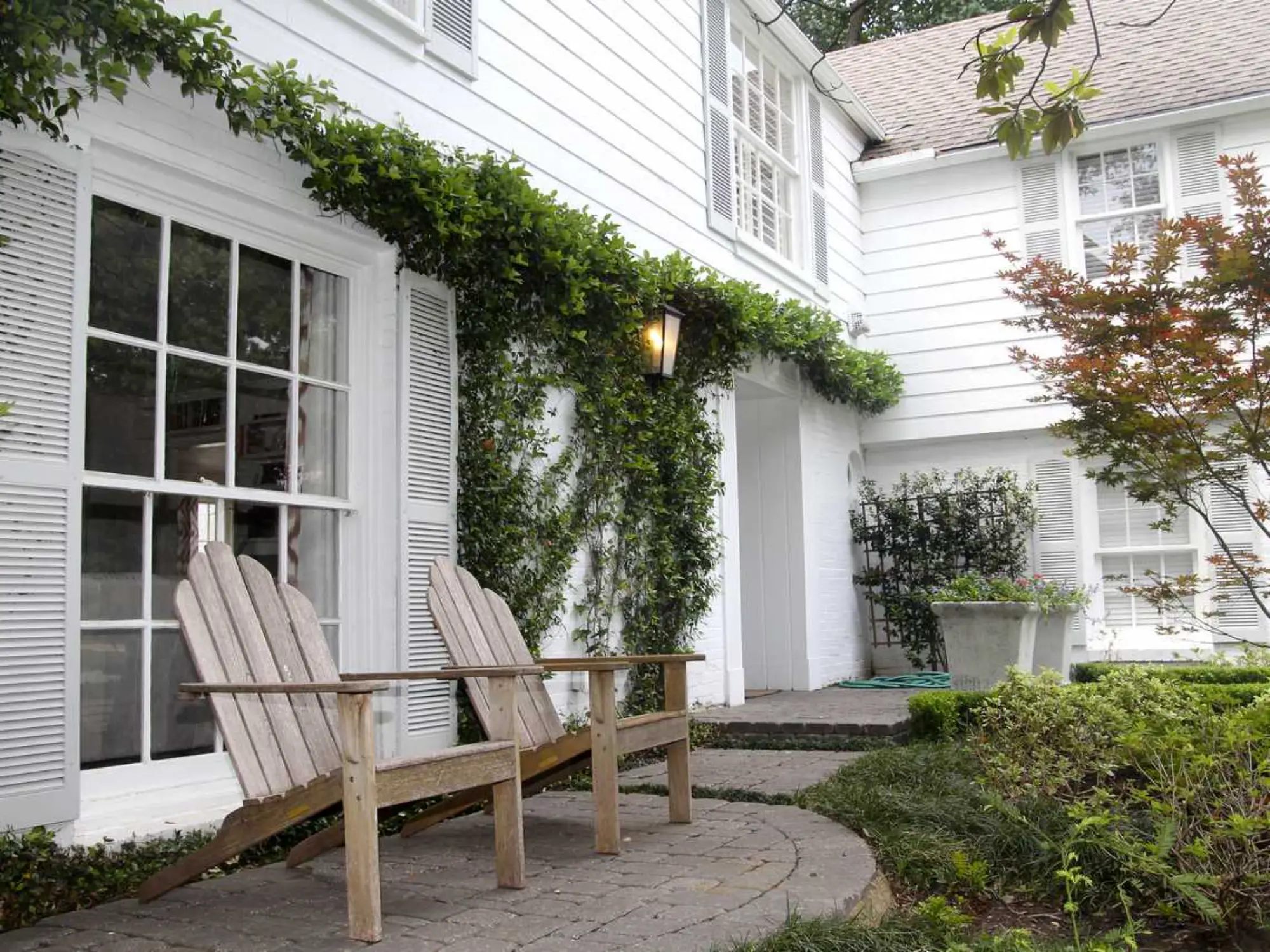 A white house with two wooden chairs placed in front, creating a cozy outdoor seating area.