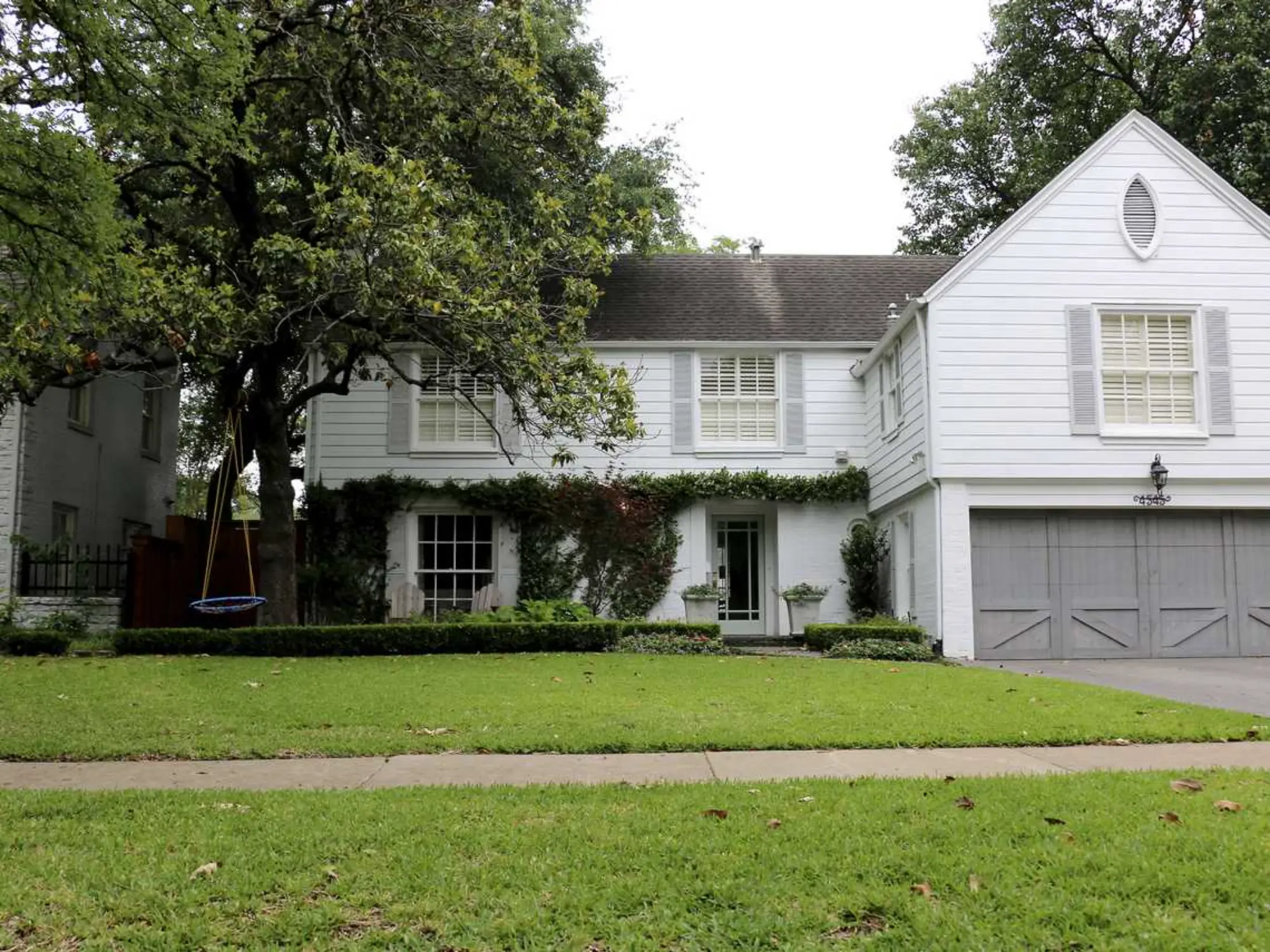 A large white house featuring a garage and a spacious driveway.