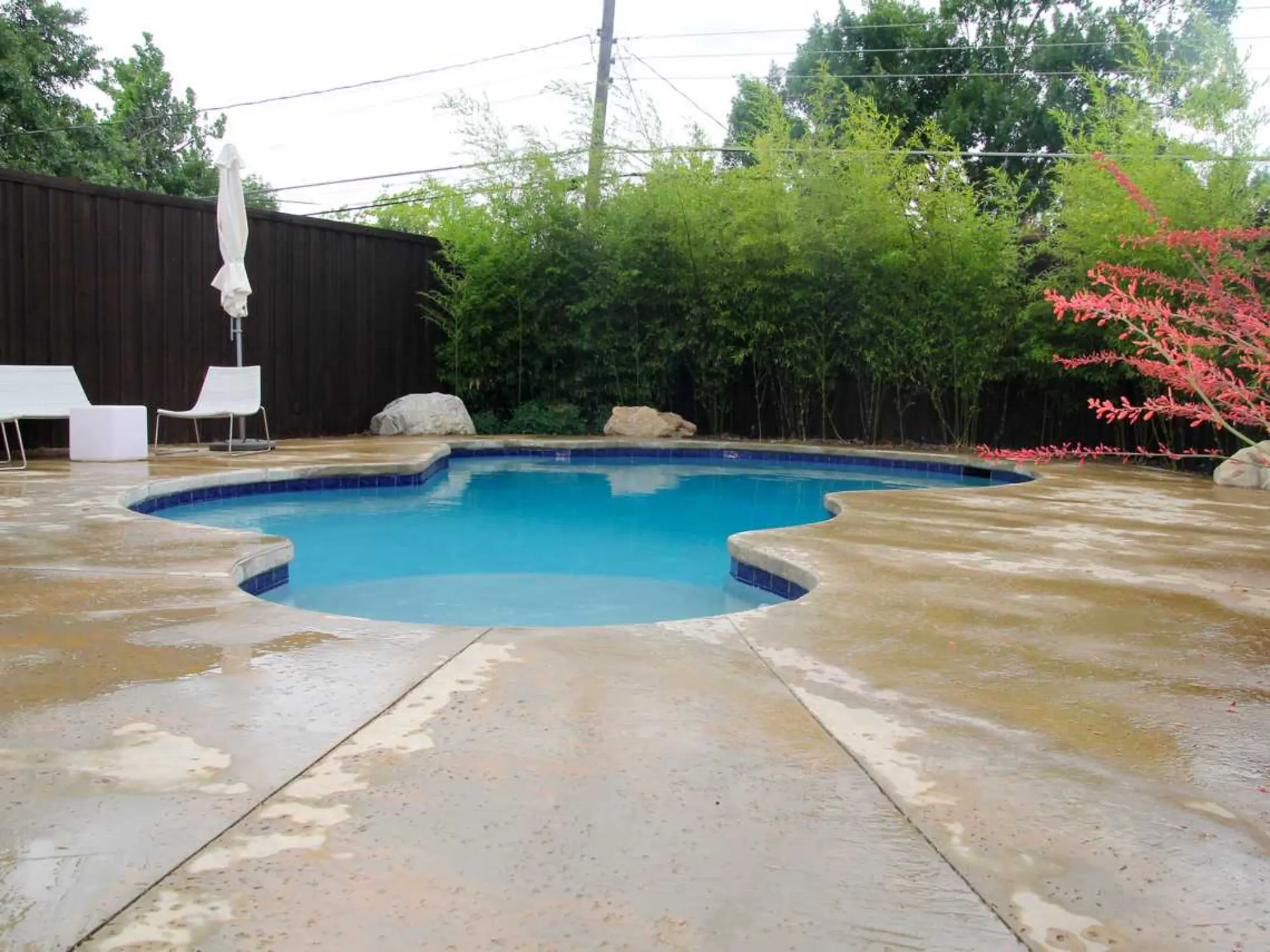 A refreshing pool in the backyard, complemented by a table and chairs for outdoor dining and leisure.