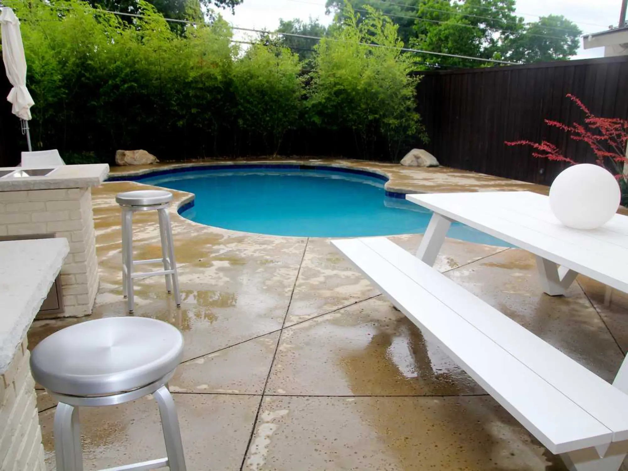 A backyard pool featuring a bar and chairs, perfect for relaxation and enjoying drinks in the sun.