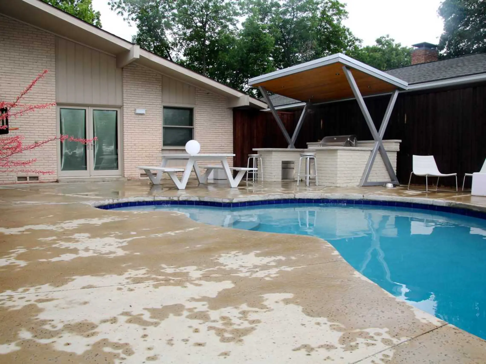  A serene backyard featuring a pool with a table and chairs, ideal for enjoying sunny days and socializing.