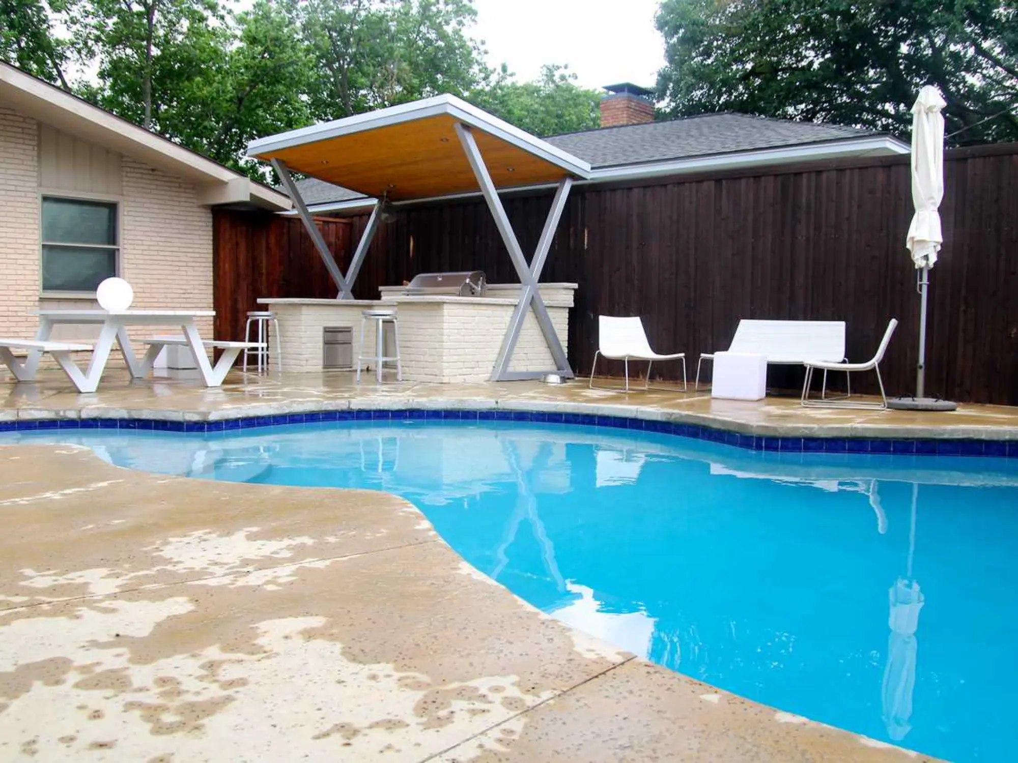 A backyard featuring a pool, patio, and grill, perfect for outdoor relaxation and entertaining.