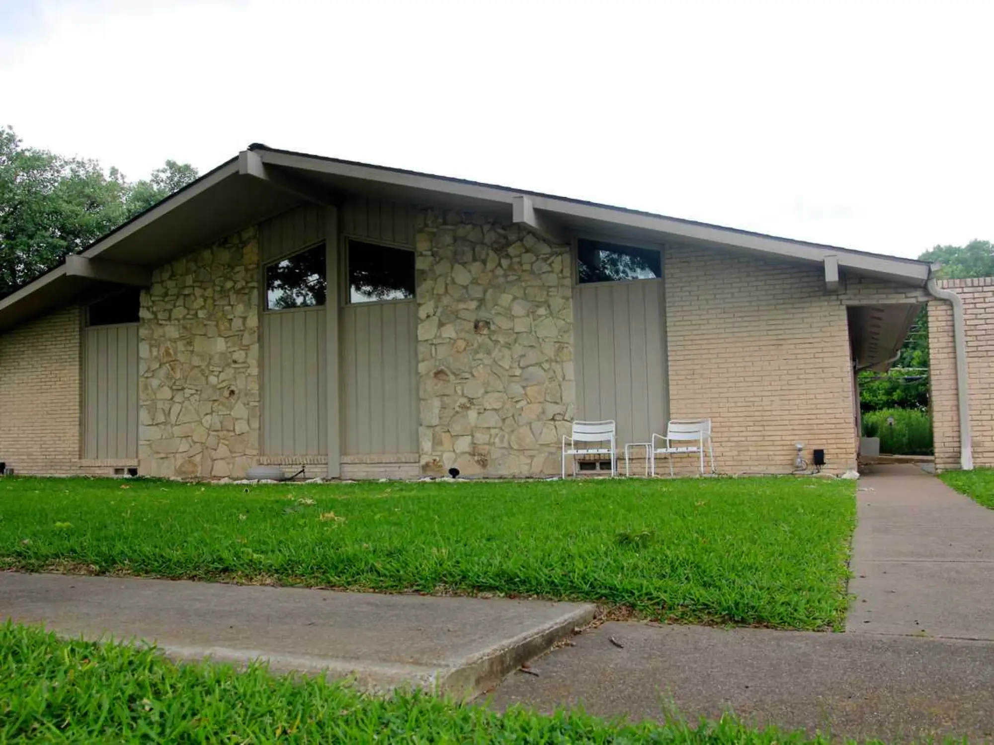 A brick building stands tall with a lush grassy area in front, creating a welcoming outdoor space.