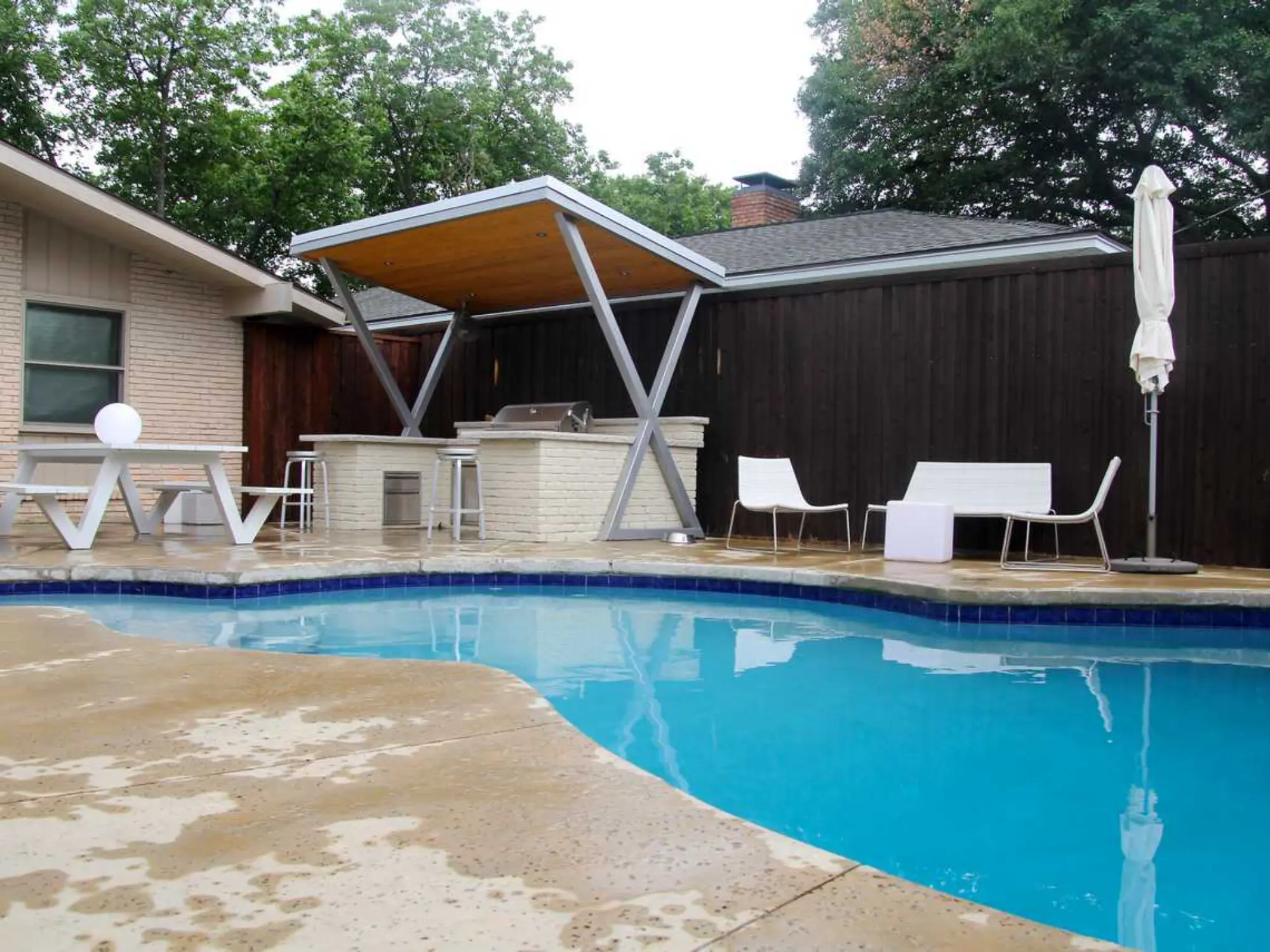 A refreshing pool in the backyard, complemented by a table and chairs for outdoor dining and leisure.