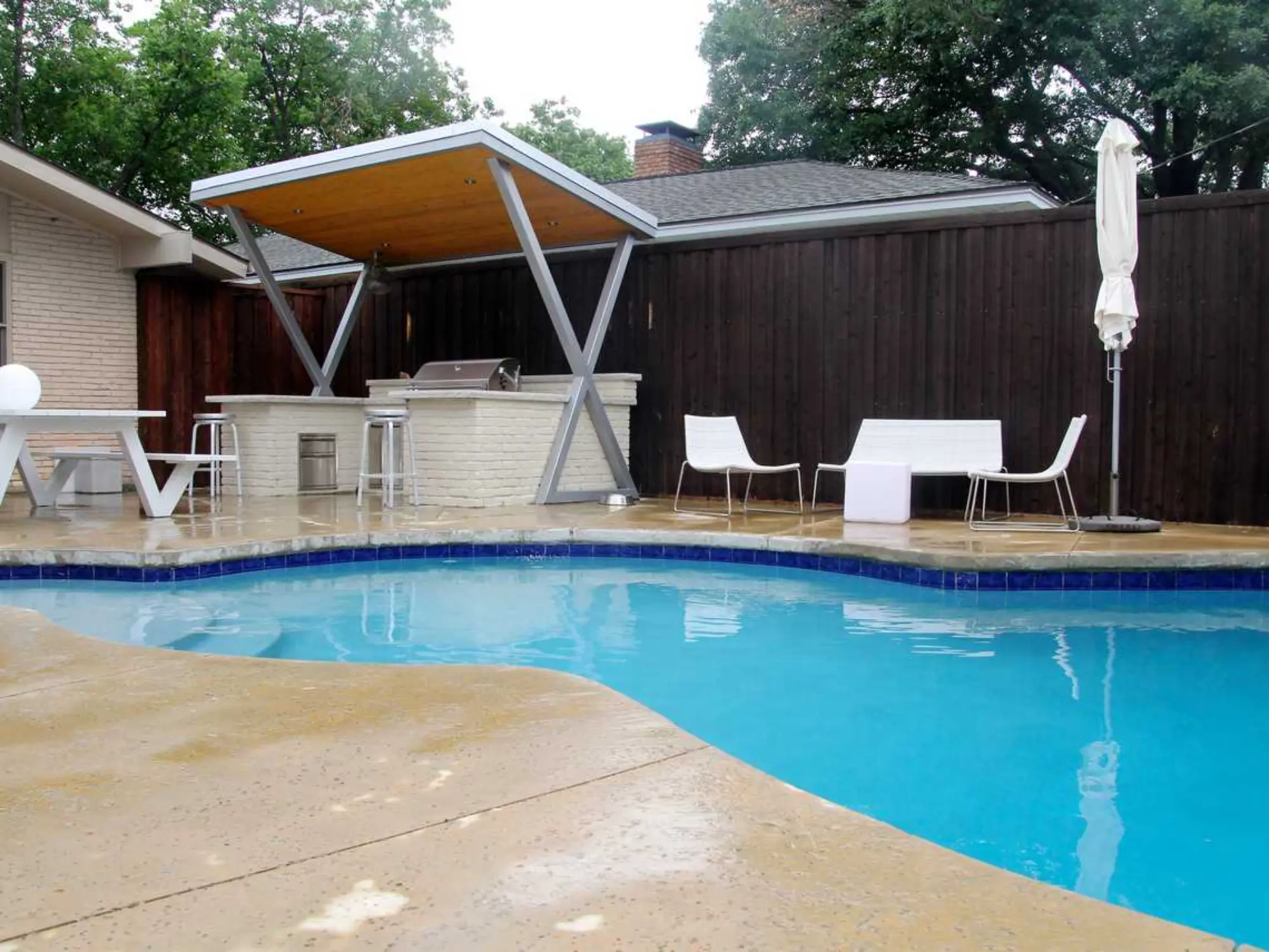A backyard featuring a pool, patio, and grill, perfect for outdoor relaxation and entertaining.