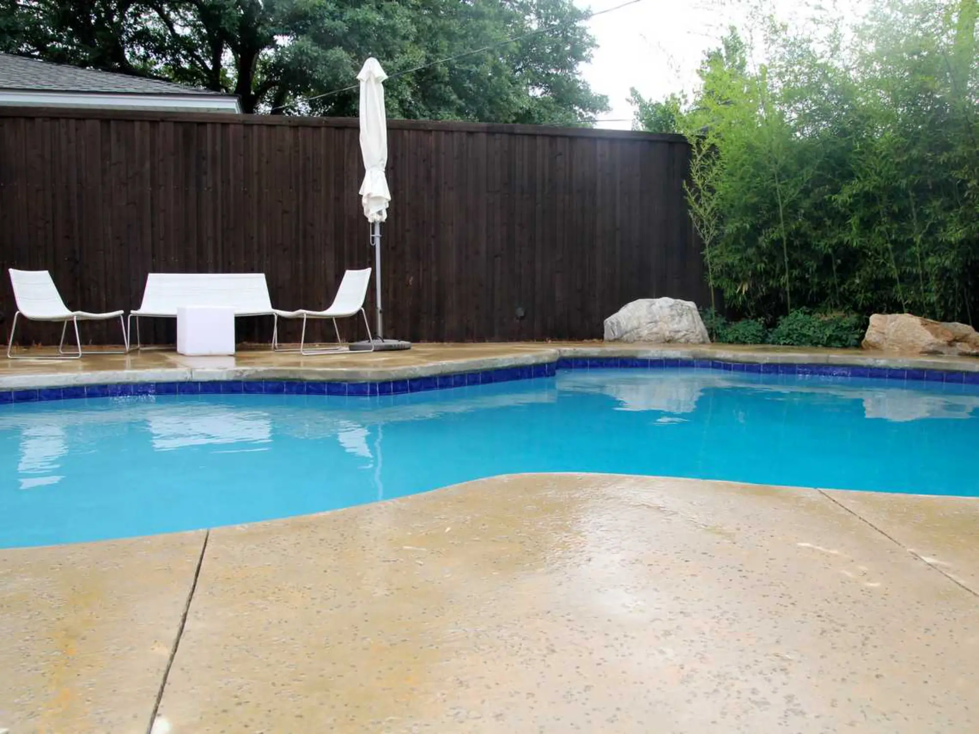 A backyard pool surrounded by a table and chairs, perfect for relaxation and outdoor gatherings.