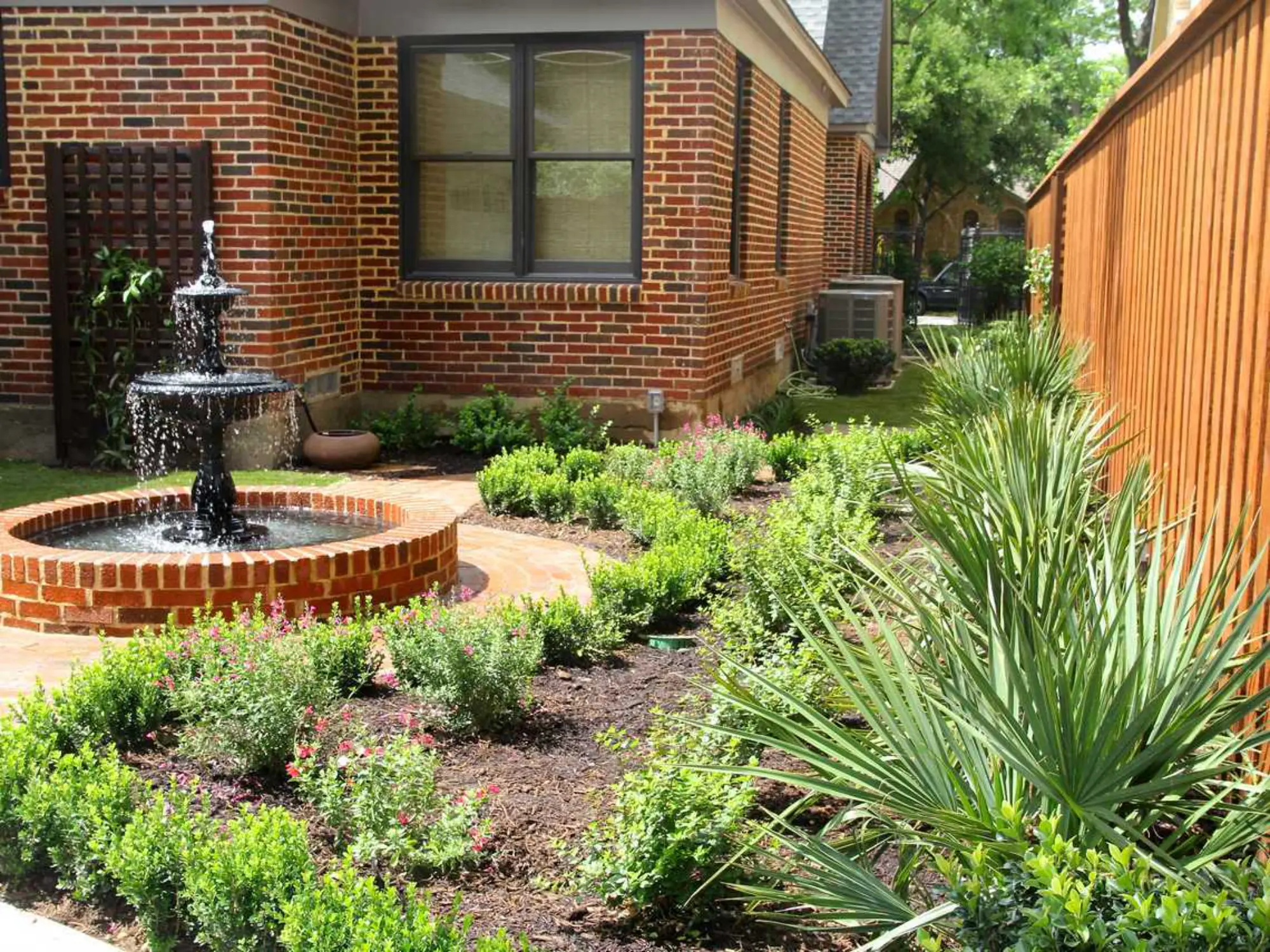 A cozy brick patio adorned with a fountain and a quaint garden, inviting tranquility and outdoor enjoyment.