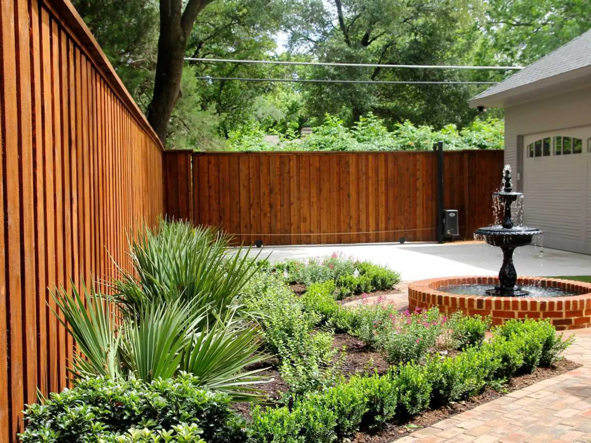 A serene backyard featuring a fountain surrounded by a wooden fence, creating a peaceful outdoor retreat.
