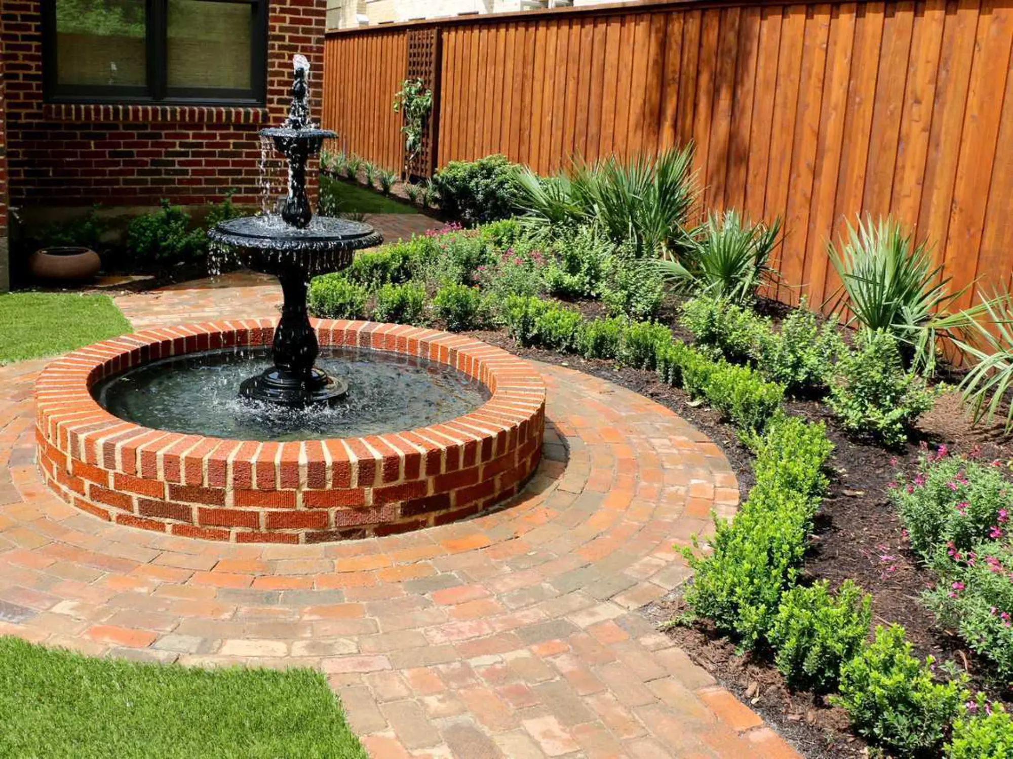 A brick fountain surrounded by a circular brick patio, creating a charming outdoor space.