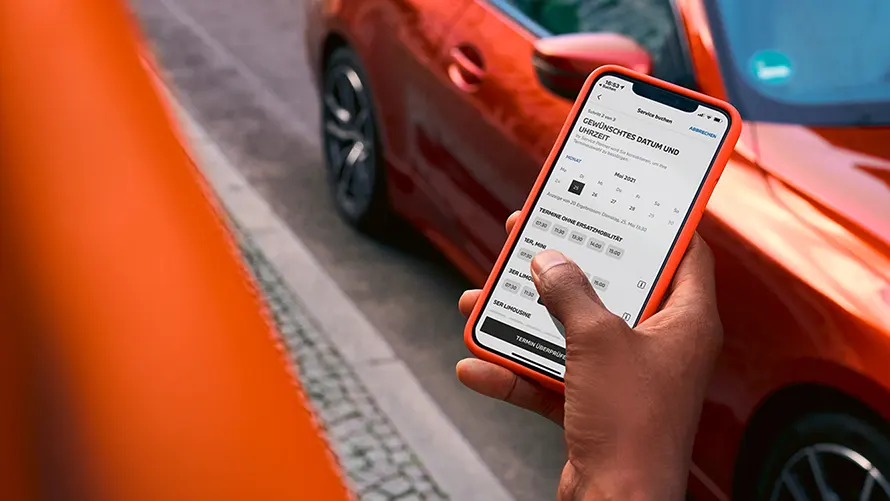 Person mit Smartphone vor einem BMW bei Nutzung der Online-Terminvereinbarung– Digitale Services und Flexibilität im Autohaus BMW Köhler in Karlstadt
