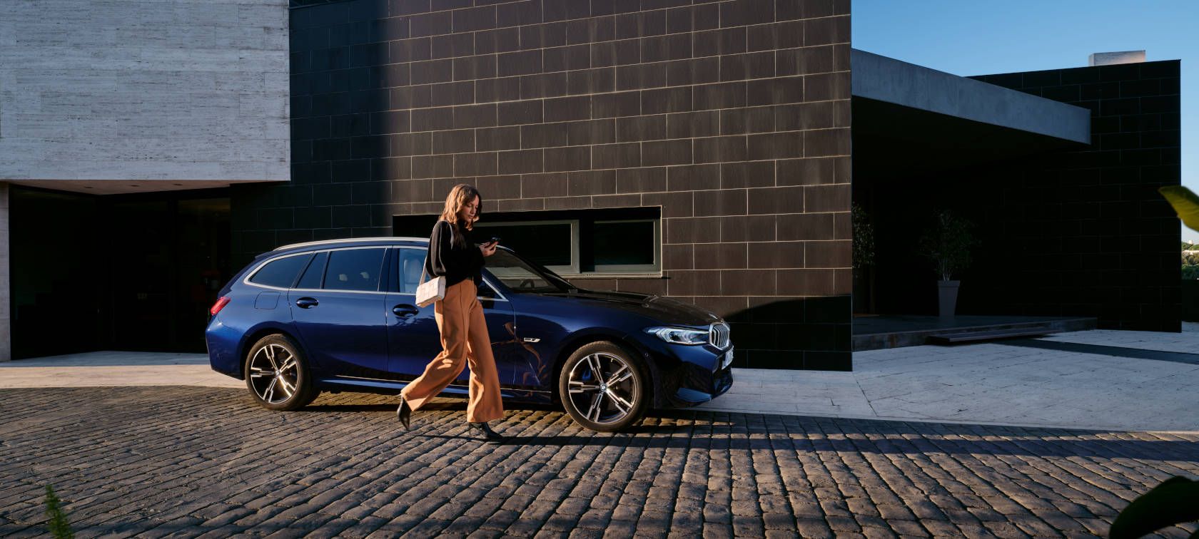Frau vor einem BMW 3er Touring bei einem Gebäude – Alltagstauglichkeit und Komfort im Autohaus BMW Köhler in Karlstadt
