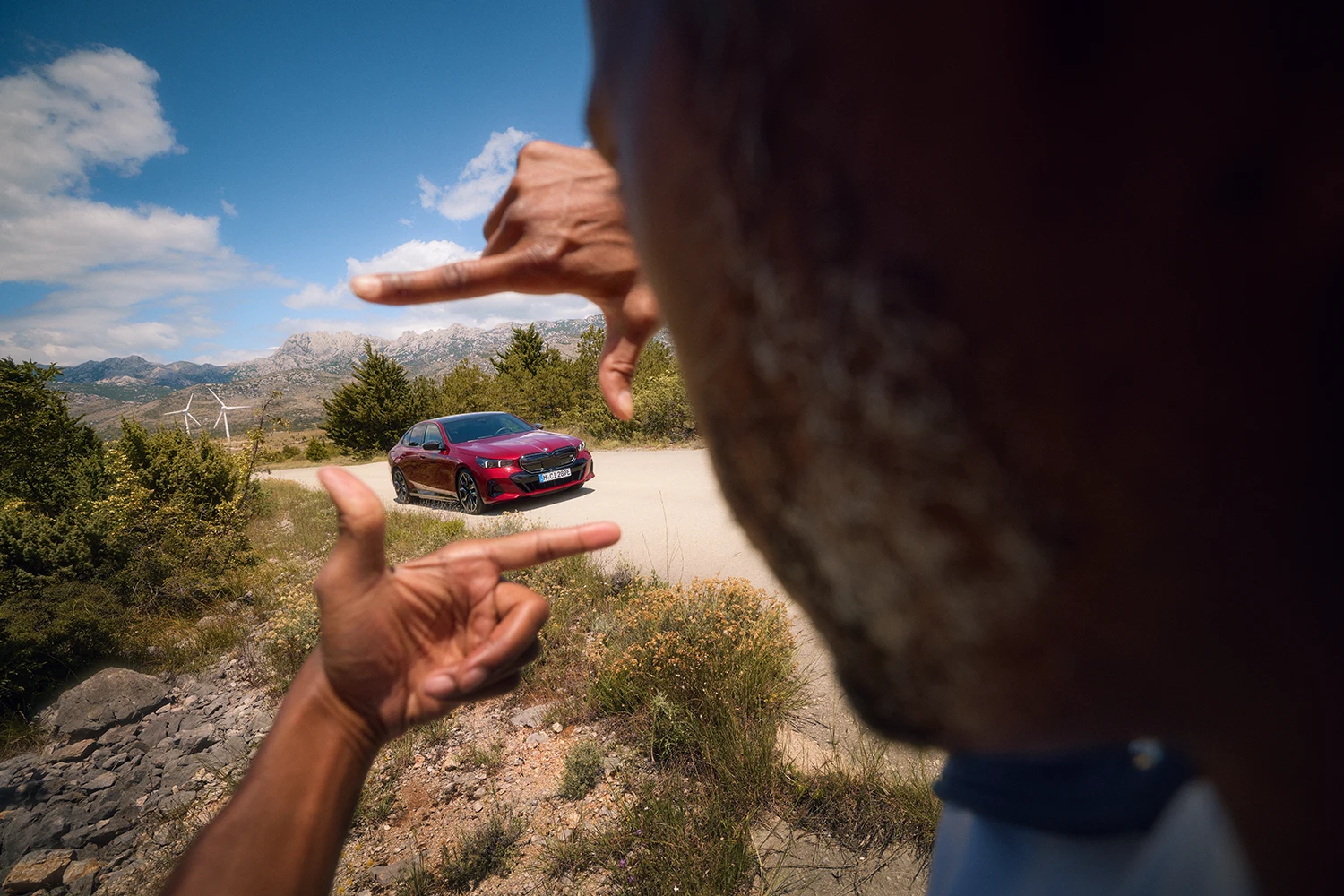 Person betrachtet ein Modellauto vor einer Berglandschaft – Leidenschaft für Details im Autohaus BMW Köhler in Karlstadt