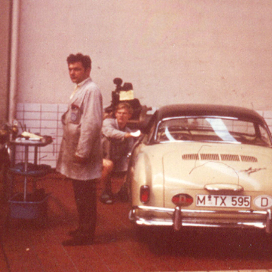 Emil Kröhler mit einem Miatrbeiter im Hintergrund der an einem historischen Fahrzeug arbeitet