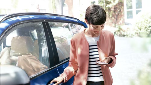 Frau mit Handy in cer Hand steigt in einen BMW –  Autohaus BMW Köhler in Karlstadt