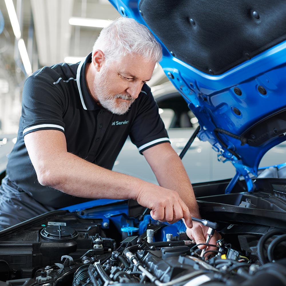Mechaniker bei der Arbeit im Motorraum eines BMW – Kompetenz und Zuverlässigkeit im Autohaus BMW Köhler in Karlstadt
