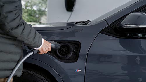 Person lädt ein BMW-Elektrofahrzeug – nachhaltige Mobilität im Autohaus BMW Köhler in Karlstadt