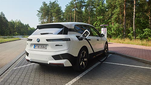 BMW iX wird geladen auf einem Parkplatz in grüner Umgebung – Zukunftsorientiertes Fahren mit BMW Köhler in Karlstadt