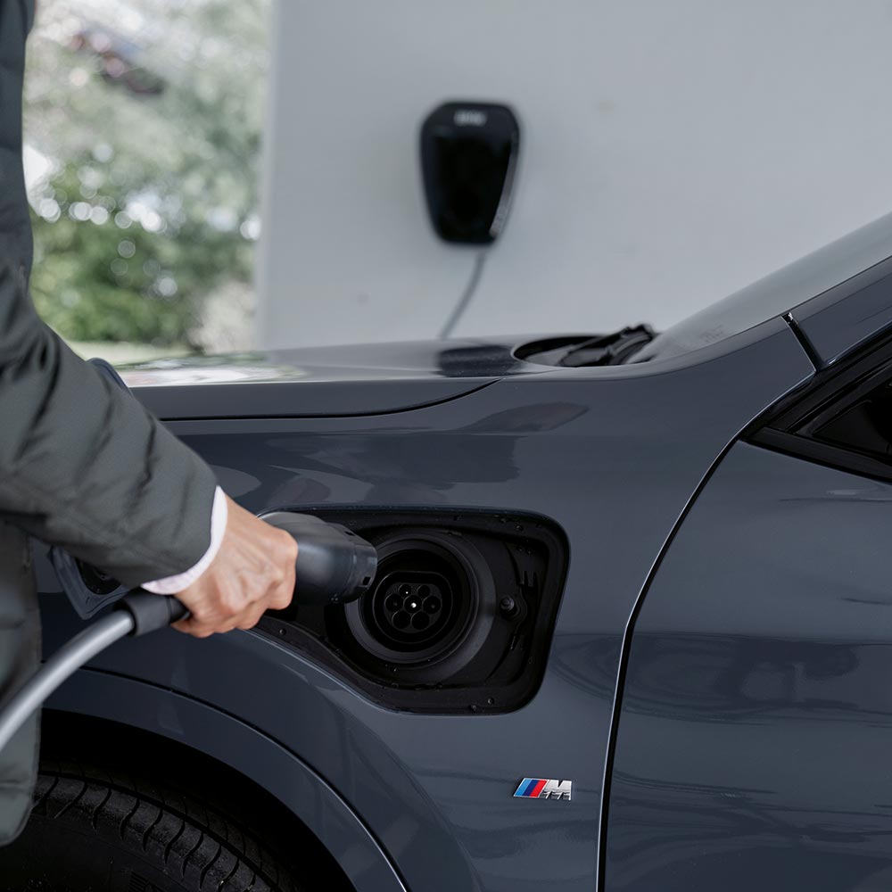 Mann beim Laden eines BMW-Elektrofahrzeugs – nachhaltige Mobilität im Autohaus BMW Köhler in Karlstadt