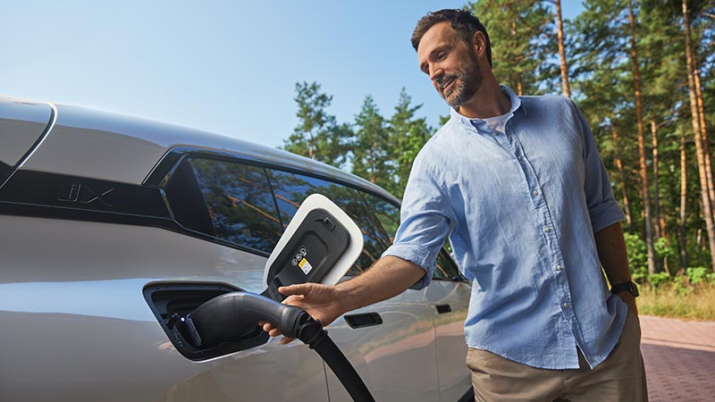 Mann lädt ein Elektrofahrzeug auf – Innovation und Komfort im Autohaus BMW Köhler in Karlstadt.