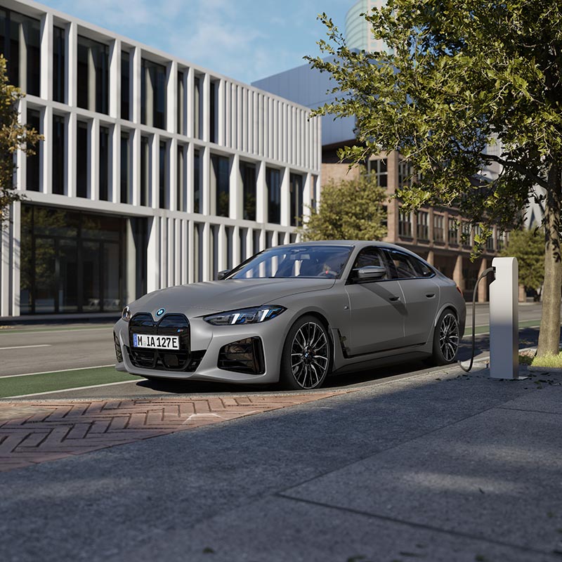 Eleganter BMW i4 der geladen wird vor moderner Architektur – Stil und Innovation im Autohaus BMW Köhler in Karlstadt