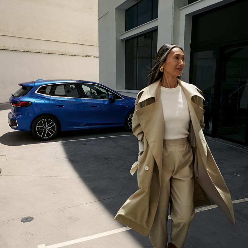 Frau neben einem blauen BMW vor moderner Architektur – Stil und Eleganz im Autohaus BMW Köhler in Karlstadt