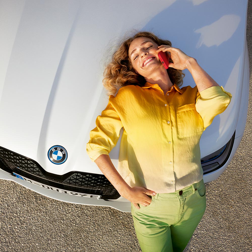 Frau lehnt an einem BMW und telefoniert – Eleganz und Alltagstauglichkeit im Autohaus BMW Köhler in Karlstadt