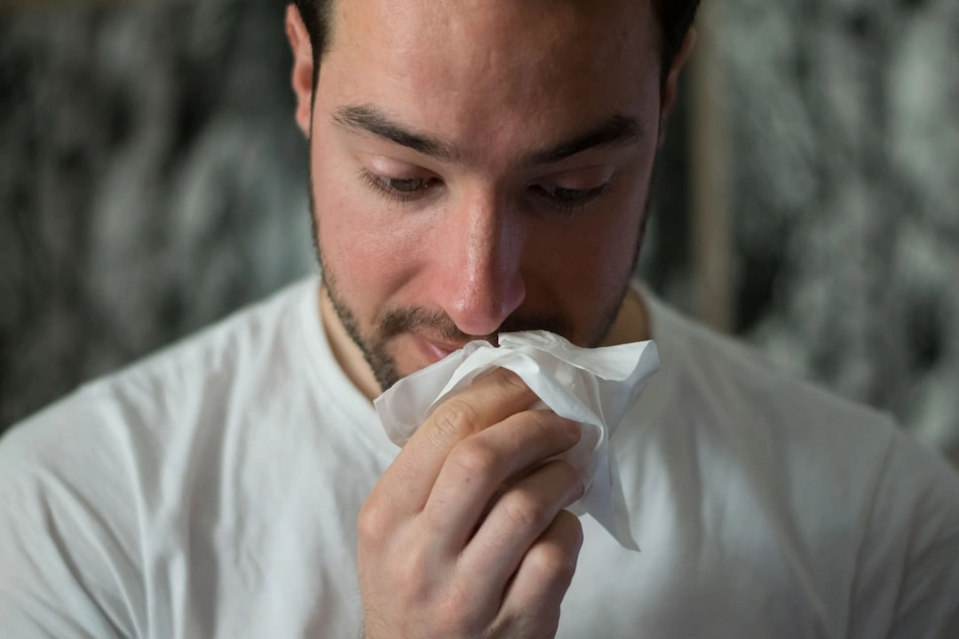 Person sneezing due to poor indoor air quality and mold spores from vents