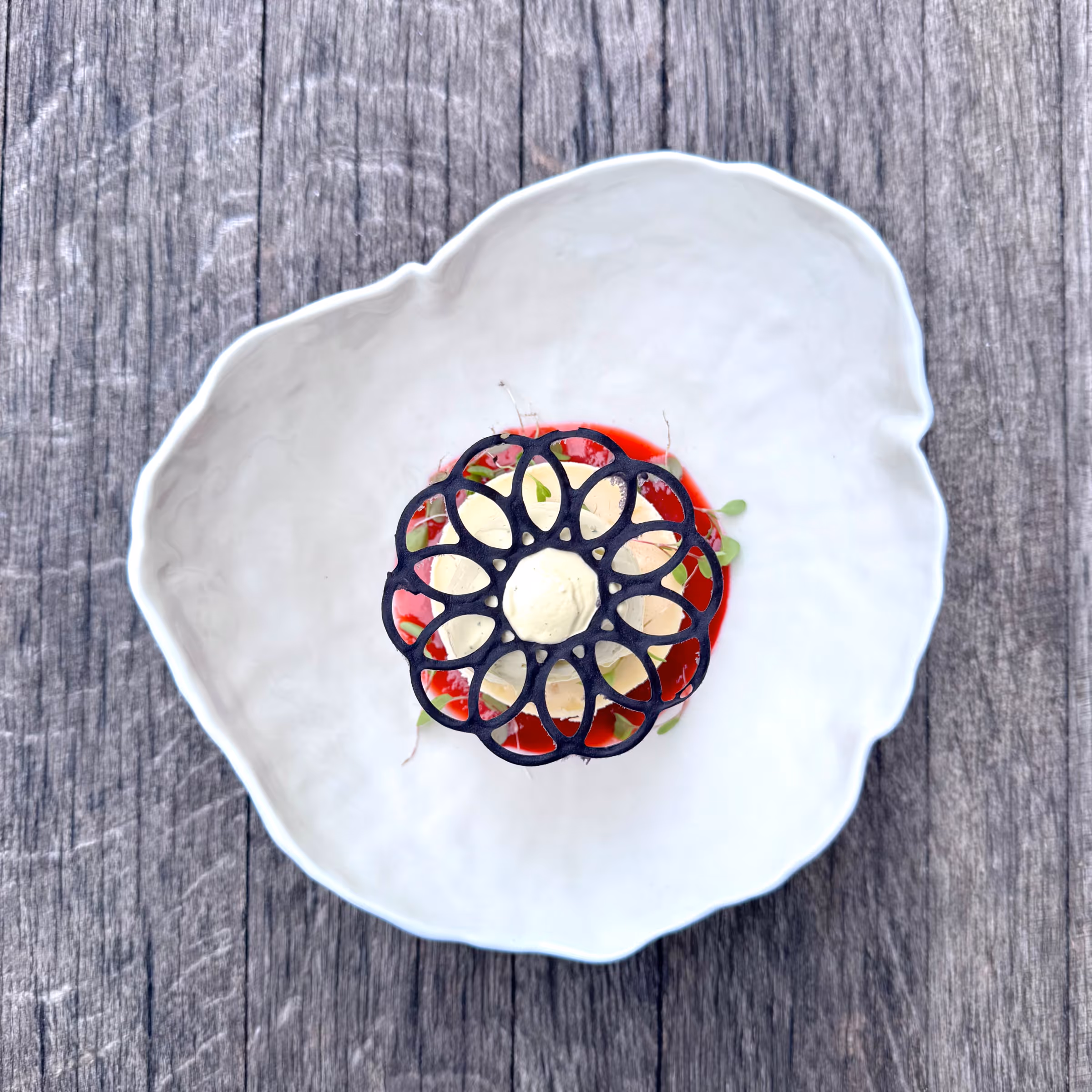 Dekoratives schwarzes Spitzenmuster auf roten Früchten in weißer Herzschale