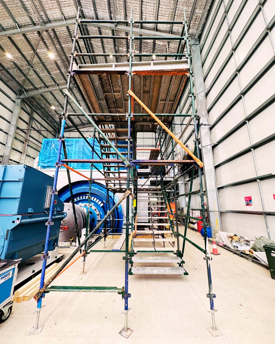 Construction workers installing scaffolding on a warehouse building structure