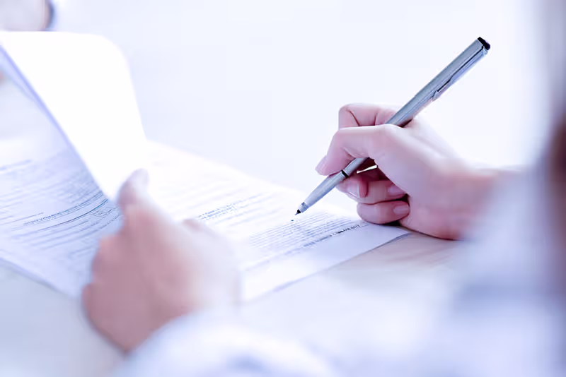 Main tenant un stylo au-dessus d'un contrat pour le signer.