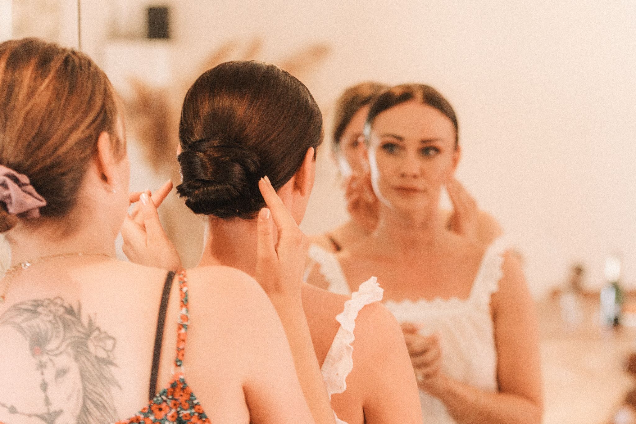 photo d'une coiffeuse à domicile faisant un chignon à une future marié
