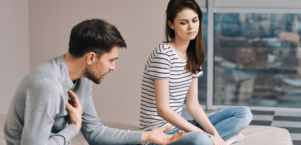 A man and a woman are sitting on the bed and talking about some issues on their relationship