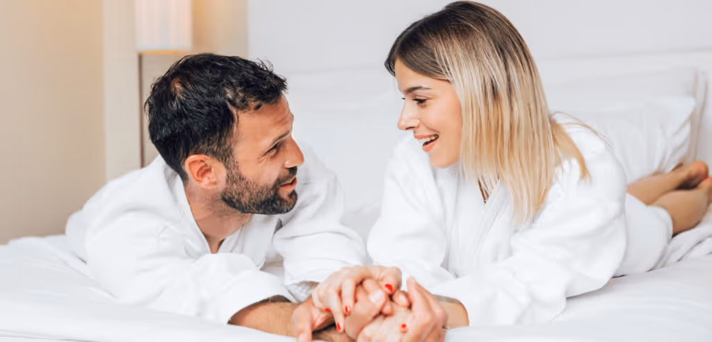 Young couple enjoying each other's company while lying in bed on a hotel room