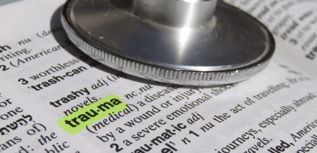 Trauma word highlighted with a stethoscope on top of dictionary 