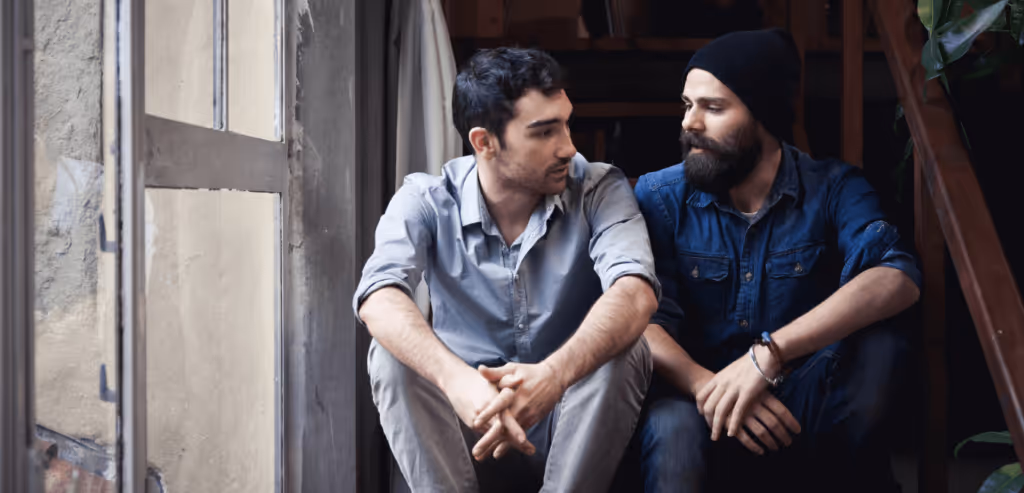 Two adult men talking seriously on the stairs, besides the window