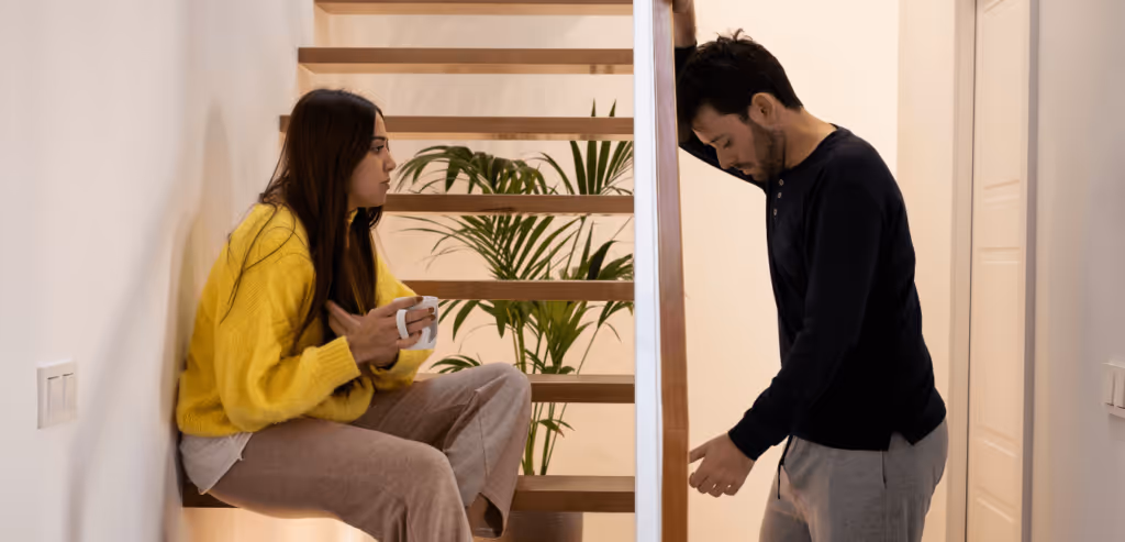 Young couple looking looking serious having a conversation inside the house in the staircase