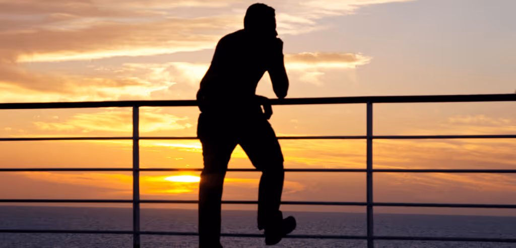 Man silhouette standing next to the railings with sunset