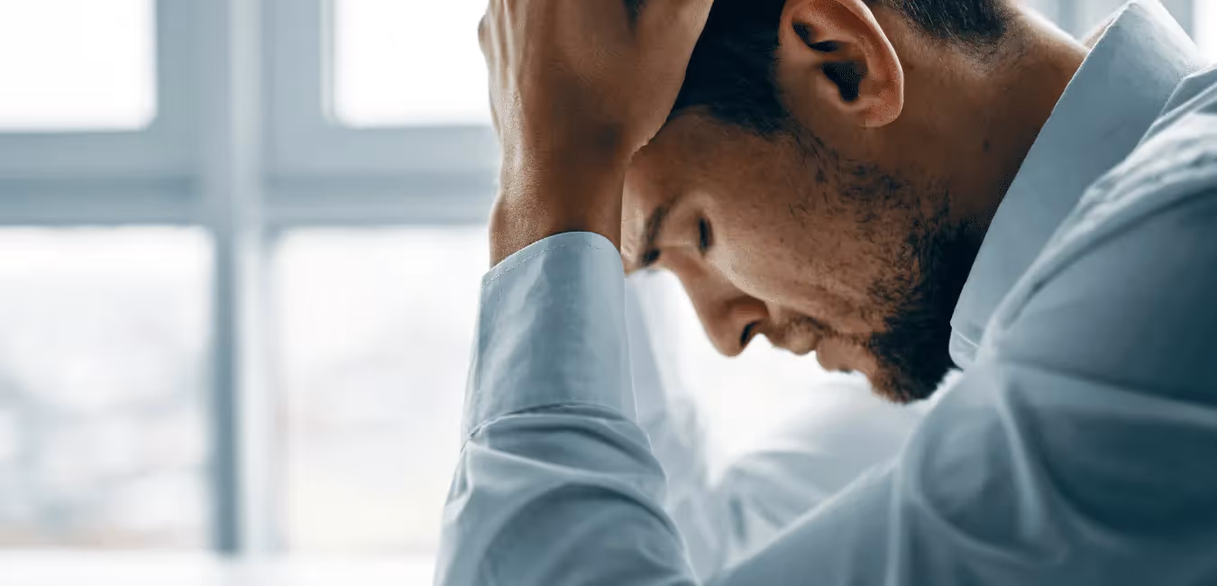 Man looking depressed sitting on the floor with head down in office